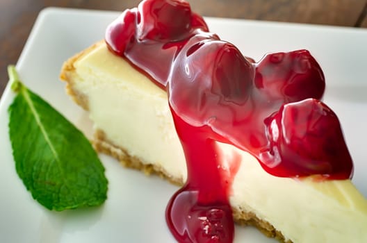 Closeup of cherries on cheesecake with mint garnish.   Shallow depth of field.  