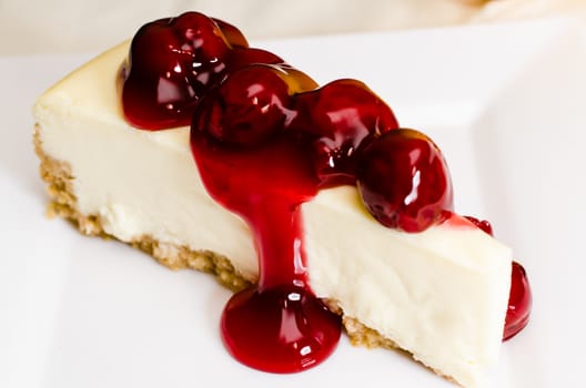 Slice of cherry cheesecake on white plate.