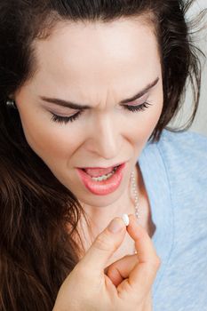 Close-up Shot of a woman suffering from pain or illness taking a pill.