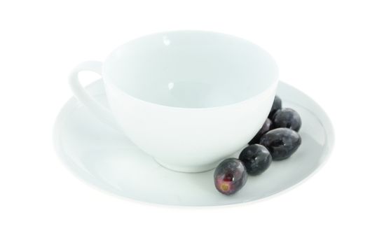 empty white cup and black grapes on plate