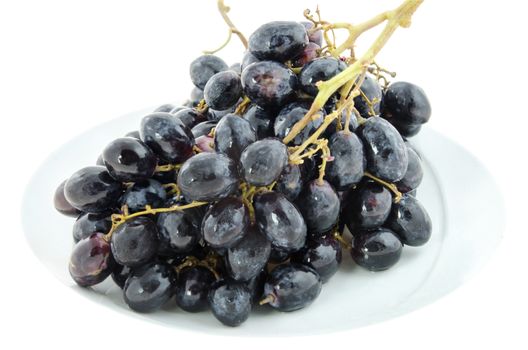 close up black  grapes  fruits on white plate over white background