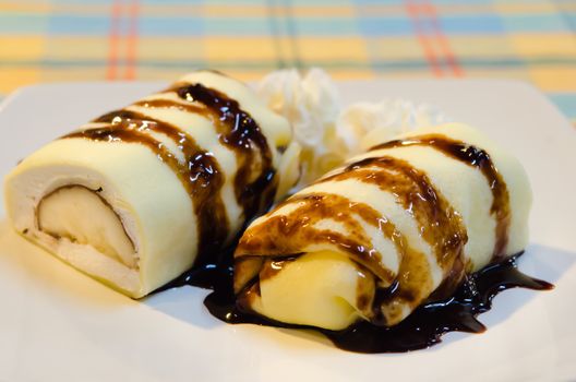 banana crepe rolls filled  with white cream and banana,   topping with chocolate  syrup