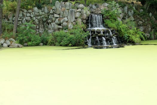 A waterfall on a algae covered pond