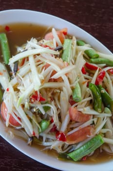 top view spicy papaya salad on white dish