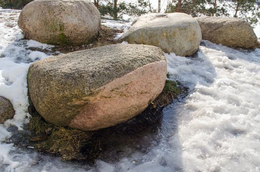 four large stones in the snow in last winter day