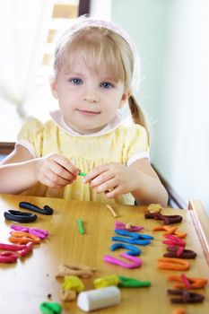 Kid sitting at table modeling colorful clay