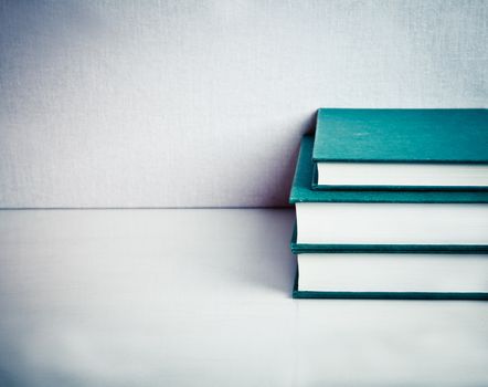 Pile composed of Tree Green Books on a white reflective table