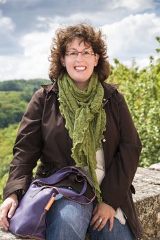 Picture of a happy adult woman sitting on a wall in spring