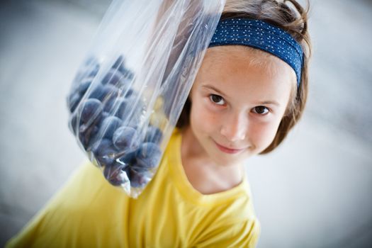 Young girl holding a prune bag freshly picked from the trees