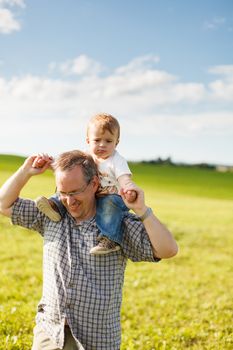 Boy riding his father's shoulders in a field