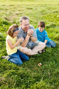 Father teaching how to whistle with grass to his kids