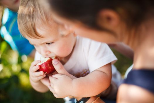 Mother helping her baby eat an apple