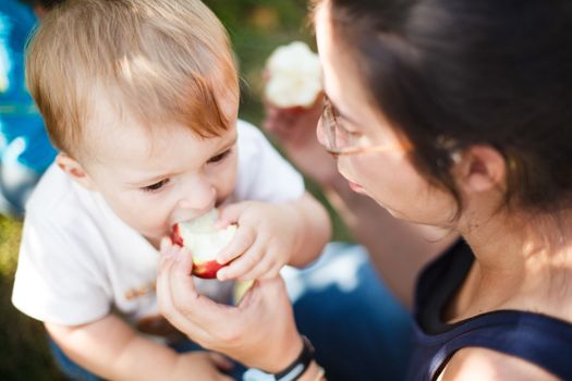 Mother helping her baby eat an apple