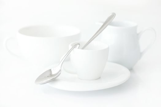 white cup with saucer, milk jug and spoon