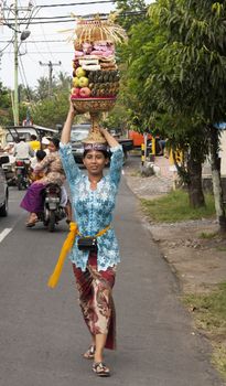BALI, INDONESIA - JUL 8TH: A woman carries a basket of fruit to the temple on July 8th 2011 during the Galungan festival which is held in the 11th week of the 210-day Pawukon calendar.