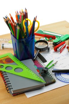 School Supplies with Note Pads, Pencils, Pens, Colored Pencils, Scissors, Pencil Sharpener, Buttons, Drawing Compass, Magnifier, Stapler, Slide-Rule and Ruler Lines on Edge of School Desk 