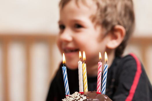 Little smiling child boy blowing birthday celebration sweet cake candle fire