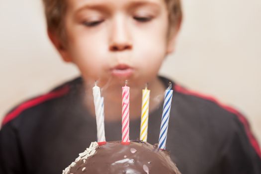 Little smiling child boy blowing birthday celebration sweet cake candle fire