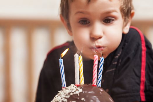 Little smiling child boy blowing birthday celebration sweet cake candle fire