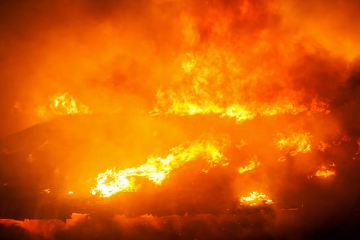 Arson or nature disaster - burning fire flame on wooden house roof