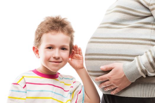 Pregnancy and new life concept - little curious smiling child boy ear listening his pregnant mother abdomen