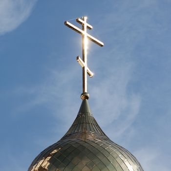 Christianity religion cross on church building dome over blue sky with clouds