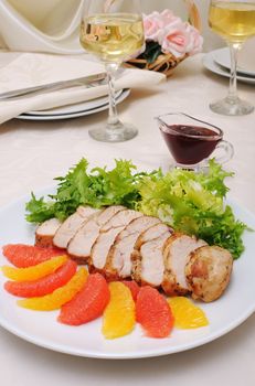 Sliced ​​baked fillet with cranberry sauce in lettuce leaves with orange and grapefruit