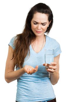 A woman suffering from headache, pain or migraine holding a painkiller pill and glass of water. Isolated on white.