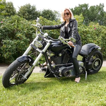 Woman dressed leather clothes on a big motorcycle
