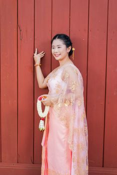 Asian Thai woman/bride in Thai wedding suit is holding flowered garland.