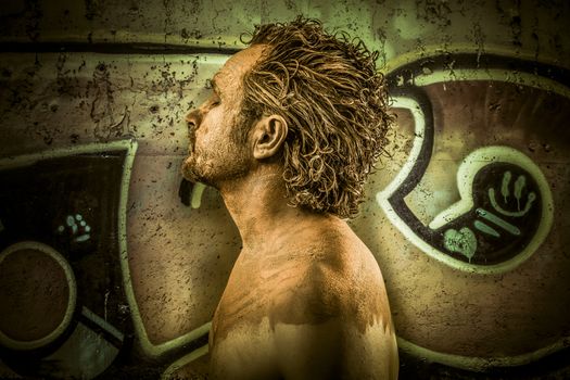 Warrior man covered in mud on grafitti background