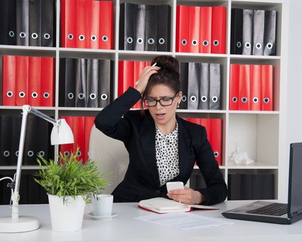 business woman in the office grabs his head