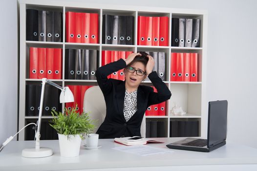 business woman in the office grabs his head