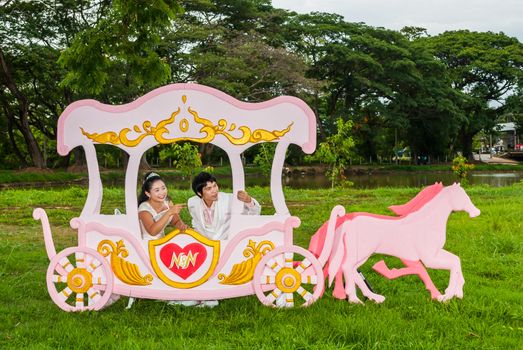 Asian Thai bridal is sitting in romantic carriage with love theme as the Prince and Princess.