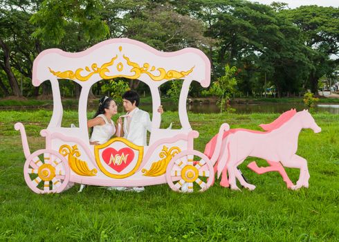 Asian Thai bride is playing her groom's necktie in romantic carriage with love theme as the Prince and Princess.