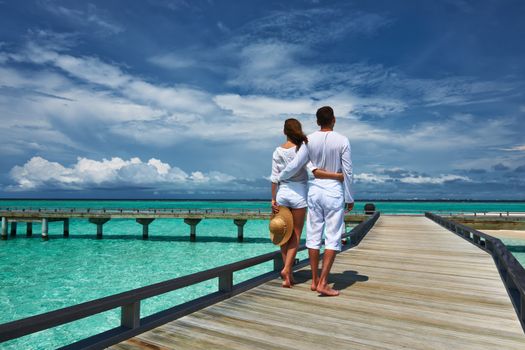 Couple on a tropical beach jetty at Maldives