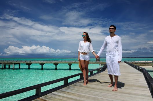 Couple on a tropical beach jetty at Maldives