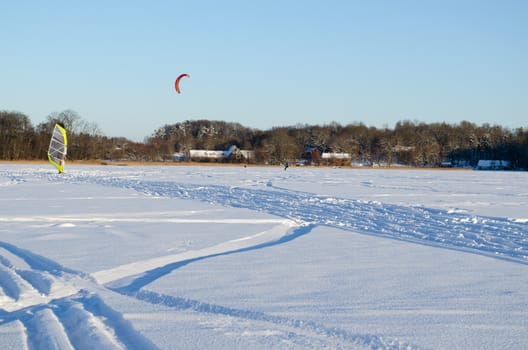 people kiteboarding and ice sailing on frozen lake in amazing cold winter day. modern recreation hobby.