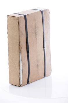 Brown rectangular cardboard box strapped with tape ready to mail through the post or for delivery by a courier
