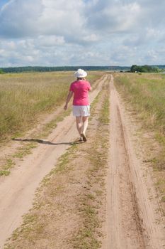 A woman walks along a country road in summer