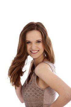 Smiling beautiful teenager playing with her long brunette hair standing sideways and looking at the camera isolated on white