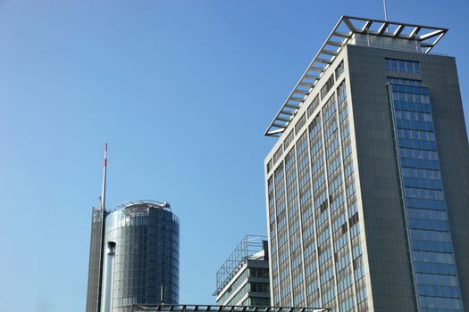 Modern urban architecture with rectangular and cylindrical highrise office blocks against a blue sky