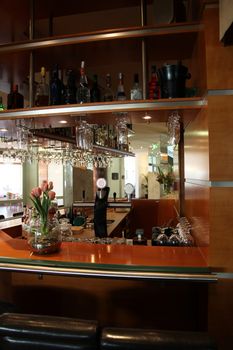 Deserted upmarket bar counter in a hotel, restaurant or club with glasses suspended from above ready for use in serving drinks