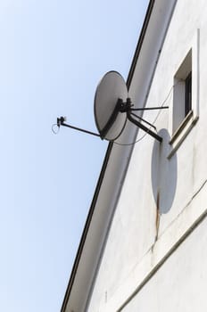 Small satellite dish mounted on a house exterior wall.