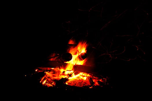 Abstract symbol of warmth and life campfire burning up firewood on dark background