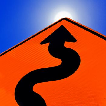 Wavy arrow on road sign pointing upward into a cloudy blue sky in a concept of achievement, advancement and success