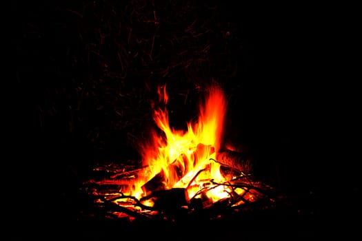 Abstract symbol of warmth and life campfire burning up firewood on dark background