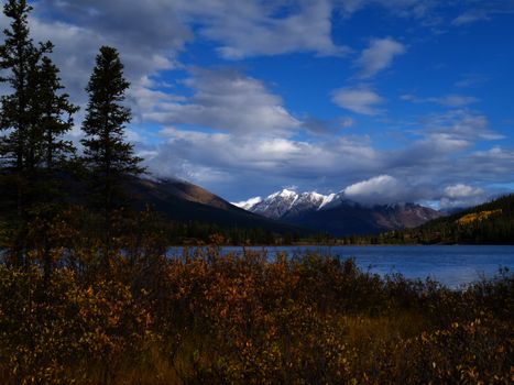 Distant mountains and fall colored willows at the shore of beautiful scenic Lapie Lake Yukon Territory Canada