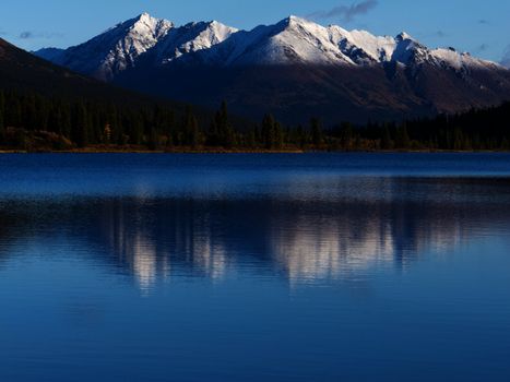 Snowcapped mountain reflection on calm surface of Lapie Lake Yukon Territory Canada