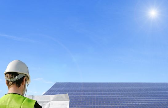 a technician reading a plan ,with solar panels in the background
